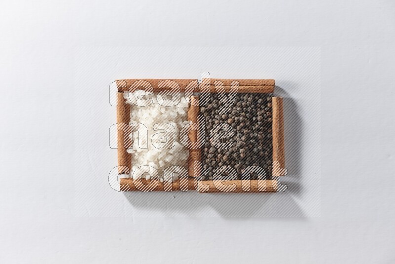 2 squares of cinnamon sticks full of black pepper and white salt on white flooring