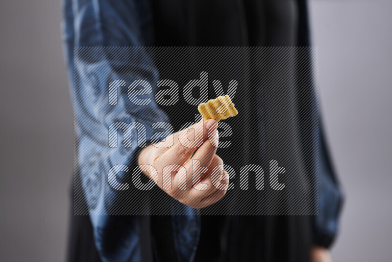 Woman in abaya holding different kinds of snacks in different positions