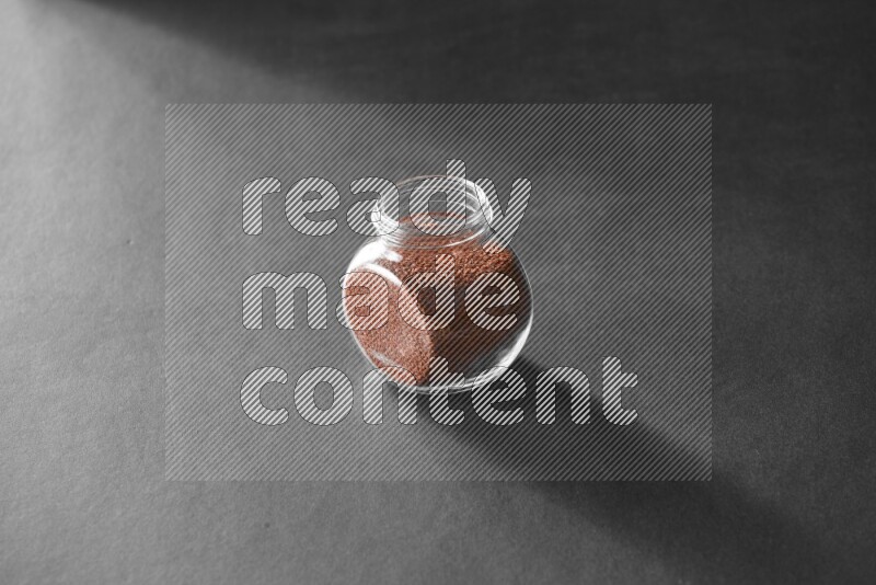 A glass spice jar full of garden cress on black flooring