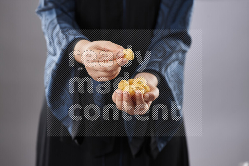 Woman in abaya holding different kinds of snacks in different positions