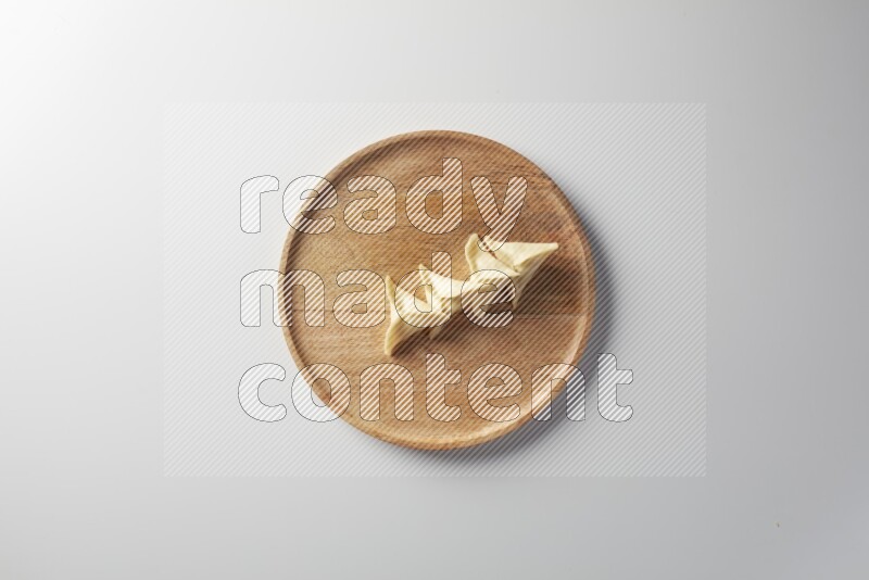 Four Sambosas on a wooden round plate on a white background