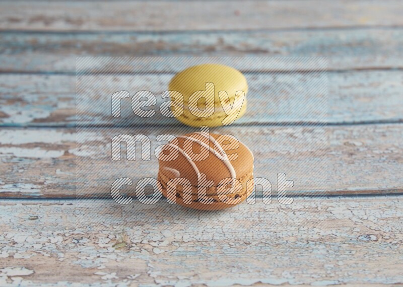 45º Shot of of two assorted Brown Irish Cream, and Yellow Lime macarons on light blue background