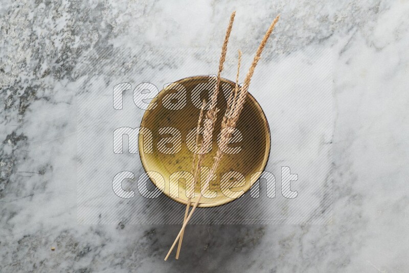 Wheat stalks on multicolored pottery oven plate on grey marble background