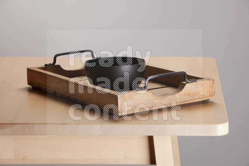 black bowl on a light colored rectangular wooden tray with handles