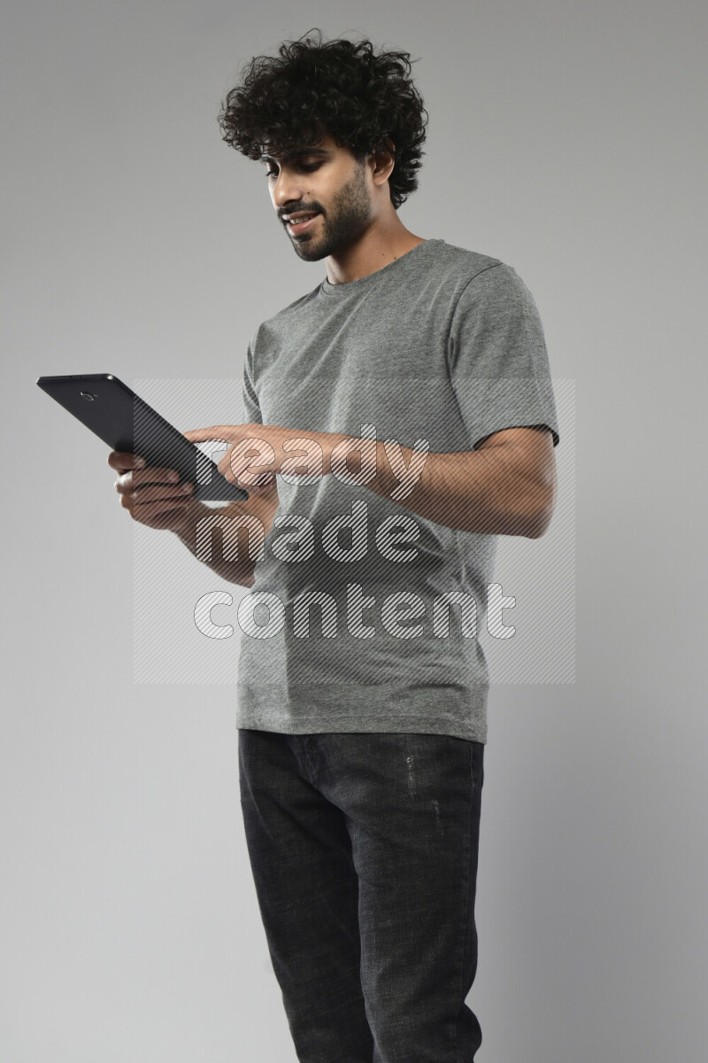 A man wearing casual standing and browsing on a tablet on white background