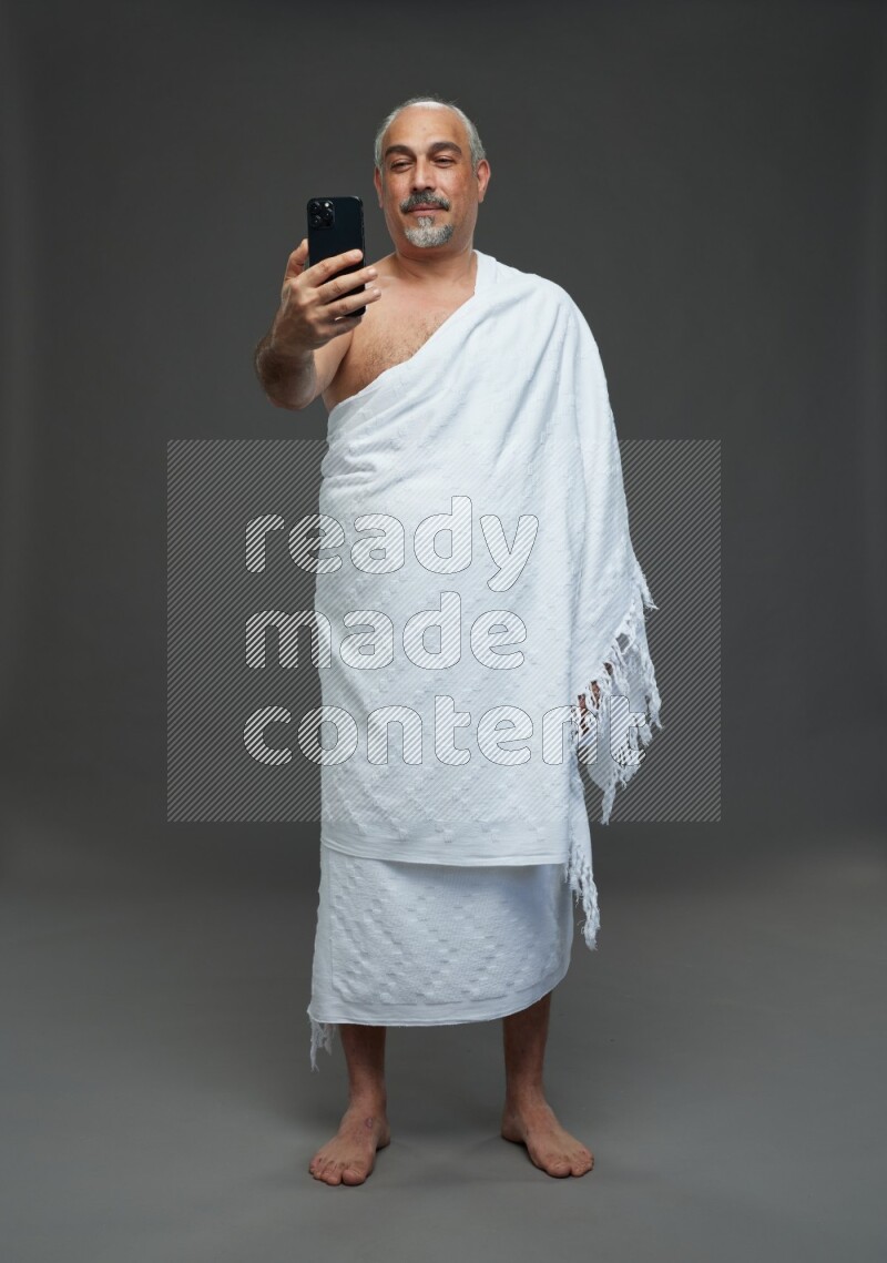 A man wearing Ehram Standing taking selfie on gray background