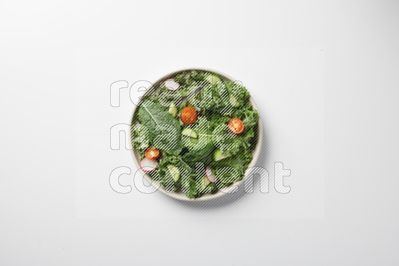 A bowl of fresh vegetables salad with kale leaves, cherry tomatoes, sliced radishes and sliced cucumber on a white background