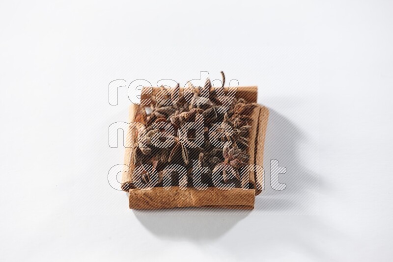 A single square of cinnamon sticks full of star anise on white flooring