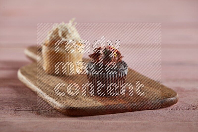 Chocolate mini cupcake topped with chocolate cream on a wooden board