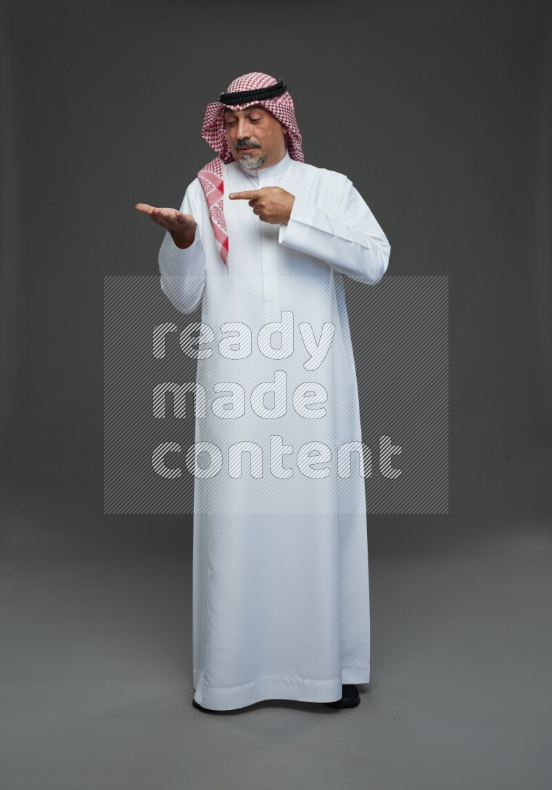 Saudi man with shomag Standing Interacting with the camera on gray background