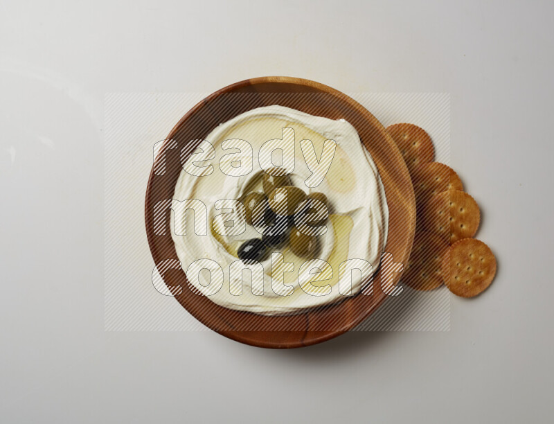 Lebnah garnished with whole olives in a wooden plate on a white background