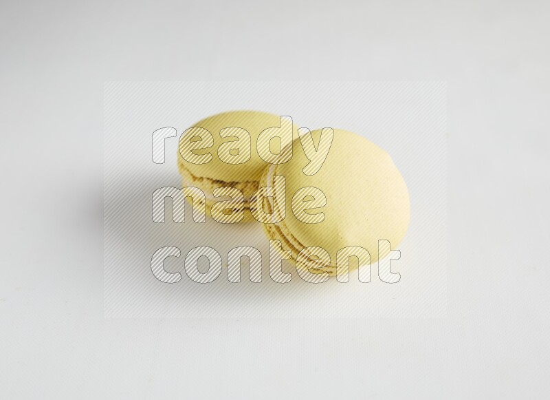 45º Shot of two Yellow Lime macarons on white background