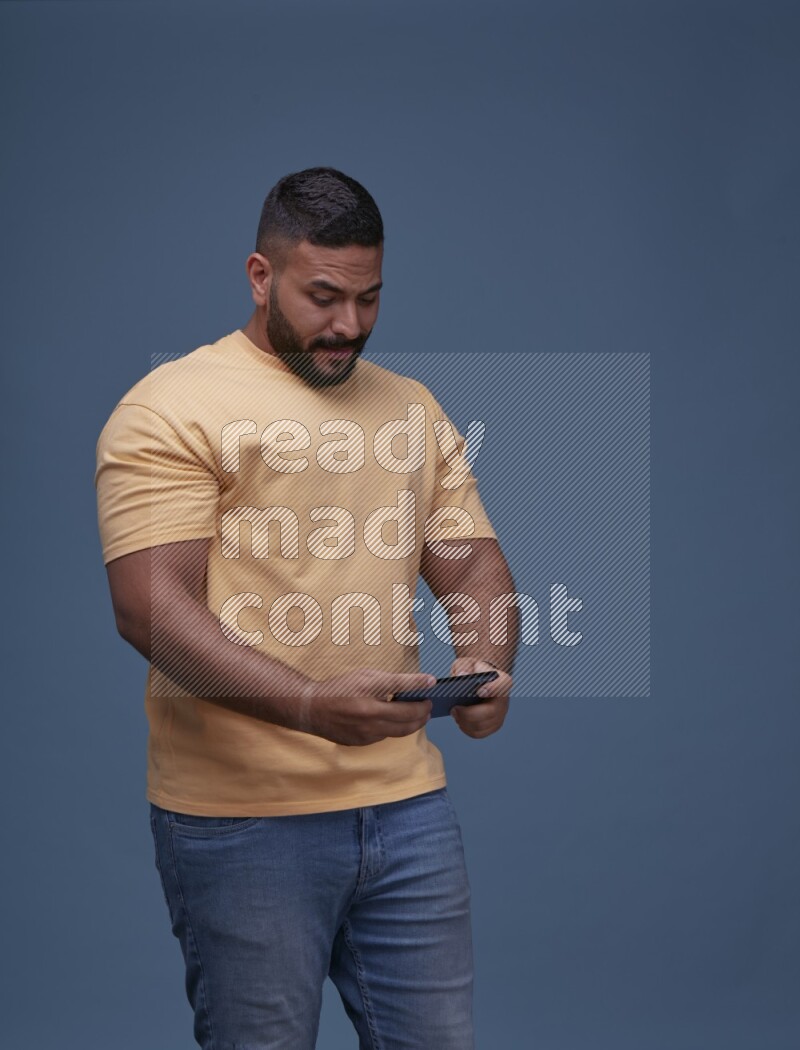 A man Playing Games on Smartphone on Blue Background wearing Orange T-shirt