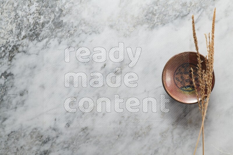 سنابل من القمح علي طبق فخاري مزخرف علي خلفية من الرخام الرمادي