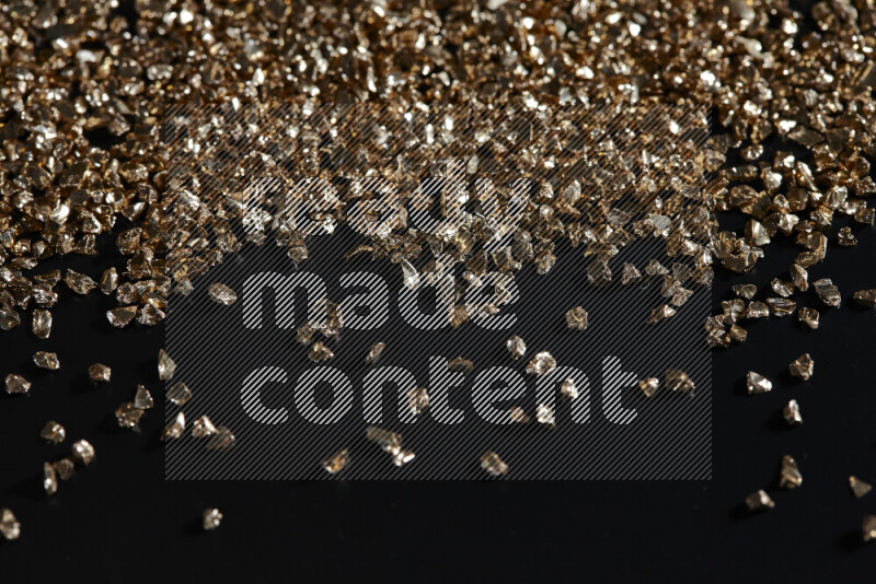 Gold shimmering fragments of glass scattered on a black background