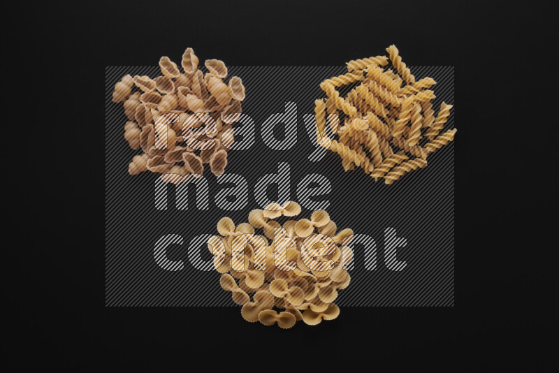 Different pasta types in bunches on black background