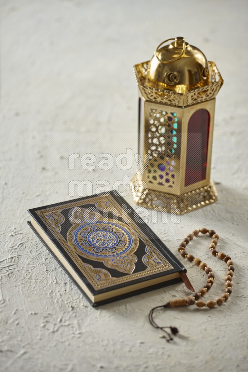 A golden lantern with different drinks, dates, nuts, prayer beads and quran on textured white background