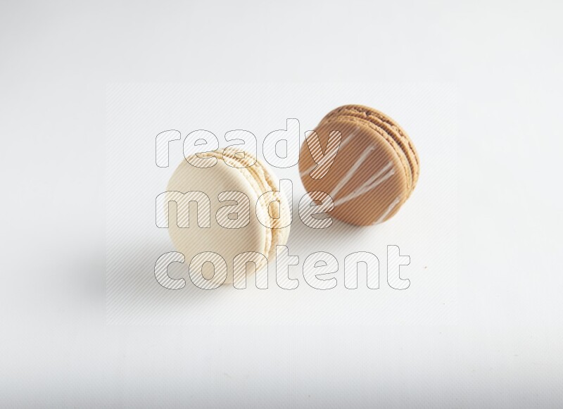 45º Shot of of two assorted Brown Irish Cream, and White Caramel fleur de sel macarons on white background