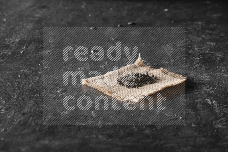 Black pepper on burlap fabric on a textured black flooring