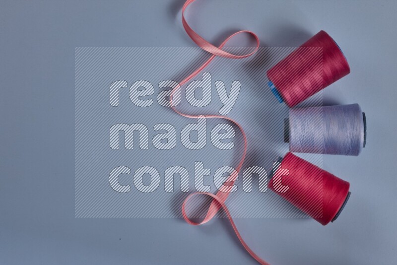 مجموعة من أدوات الخياطة والتفصيل زهرية اللون على خلفية زرقاء