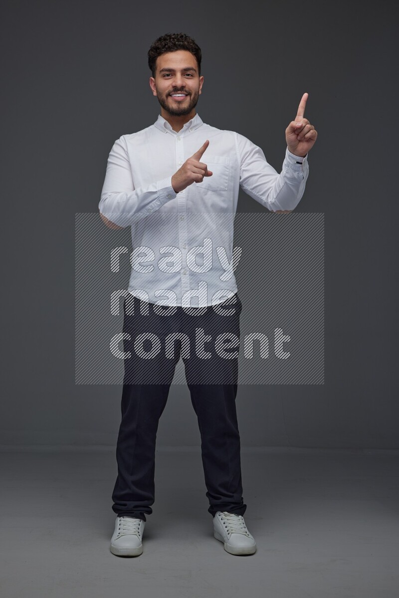 A man wearing smart casual standing and making multi hand gestures eye level on a gray background