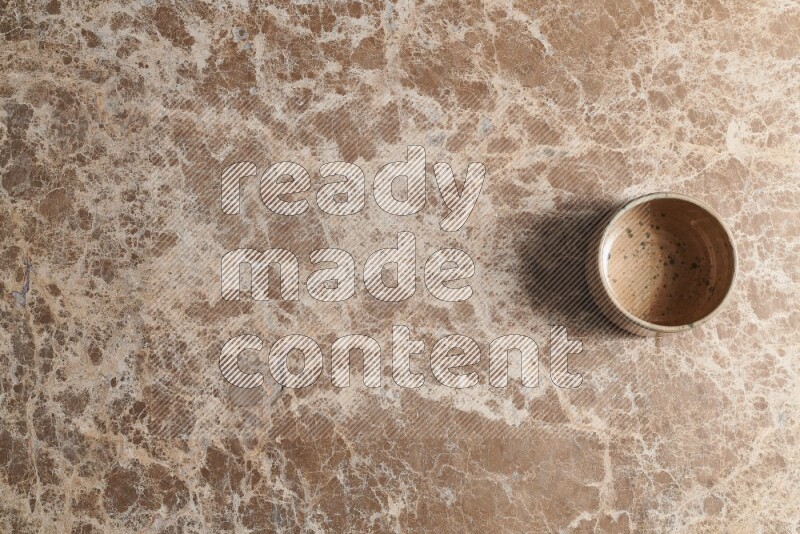 A multicolored pottery bowl on beige marble background