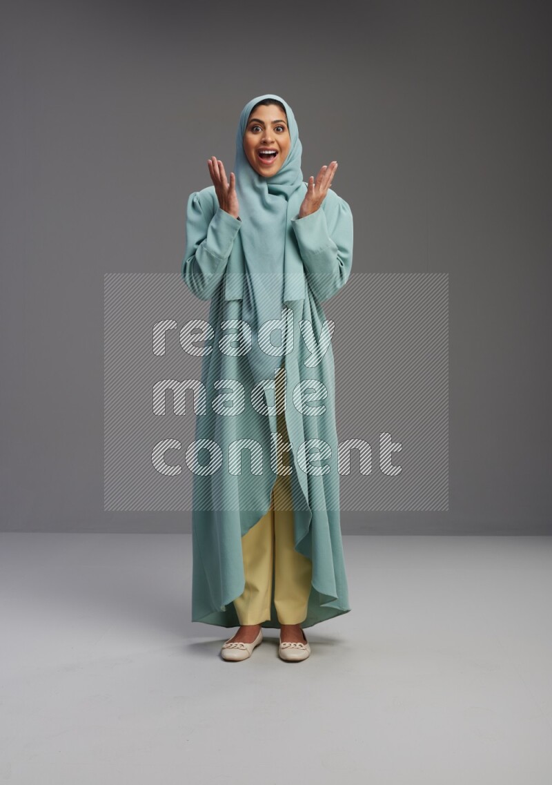 Saudi Woman wearing Abaya standing interacting with the camera on Gray background