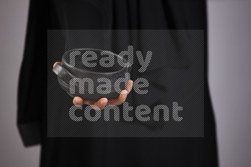A woman in black abaya holding different pottery essentials in different positions