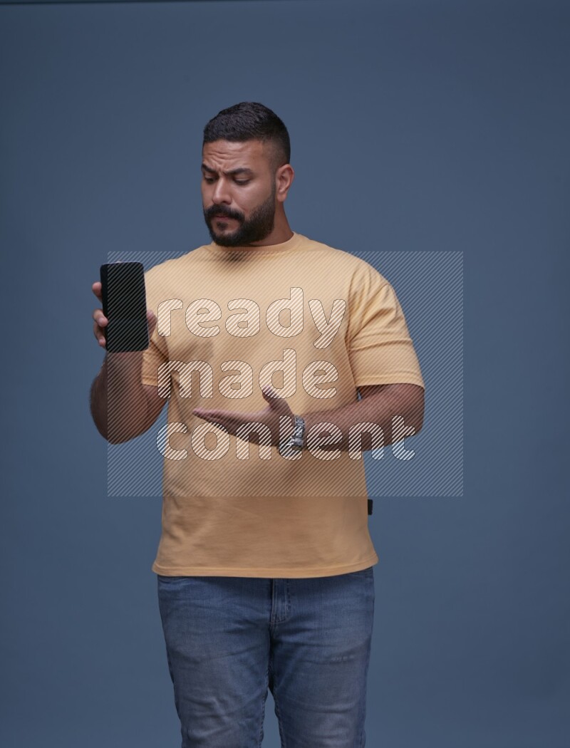 A man Showing His Smart Phone on Blue Background wearing Orange T-shirt