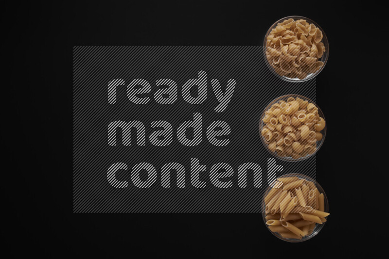 Different pasta types in 3 glass bowls on black background