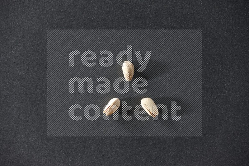 3 pistachios on a black background in different angles