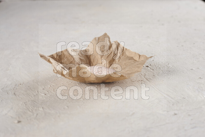 A crumpled piece of paper full of pink himalayan salt on white background