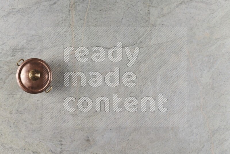 A small copper pot on grey marble background