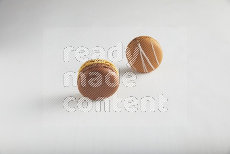 45º Shot of of two assorted Brown Irish Cream, and Yellow, and Brown Chai Latte macarons on white background