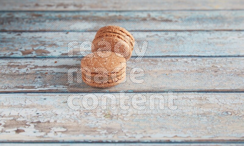 45º Shot of two Brown Hazelnuts macarons on light blue wooden background