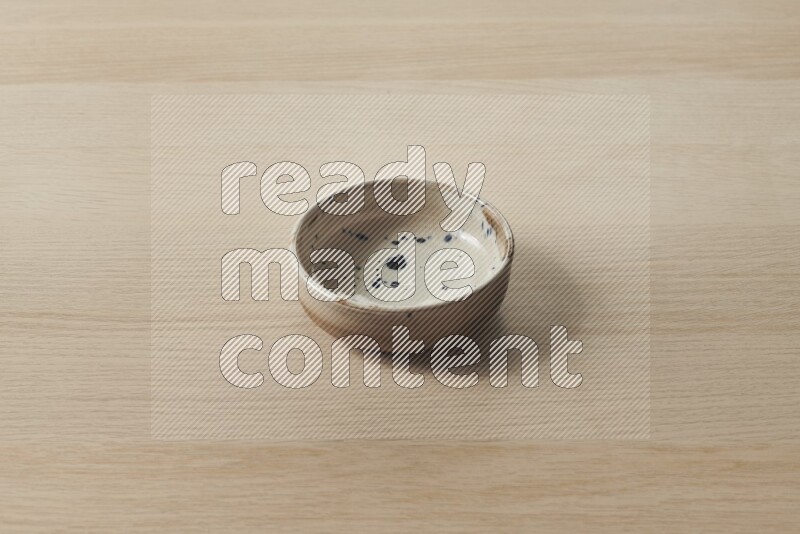 A multicolored pottery plate on light wooden background