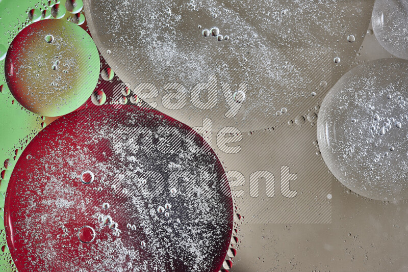 Close-ups of abstract oil bubbles on water surface in shades of brown, green and red
