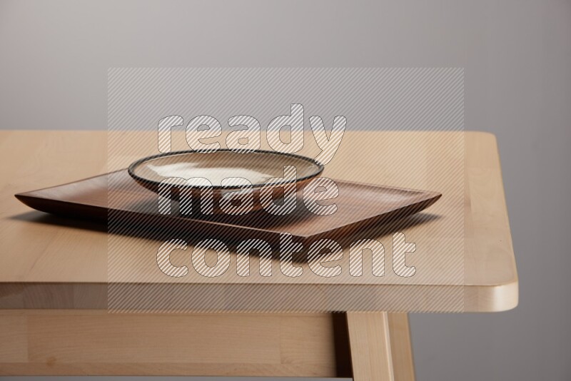 multicolored plate on a rectangular wooden tray on the edge of wooden table