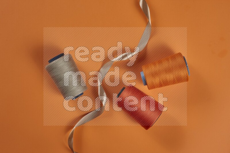 A brown collection of sewing and tailoring tools arranged on a orange background
