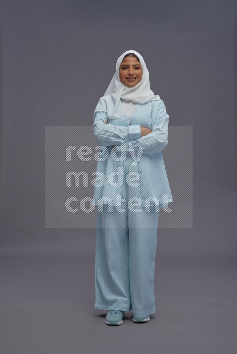 Saudi woman wearing hijab clothes standing with crossed arms on gray background