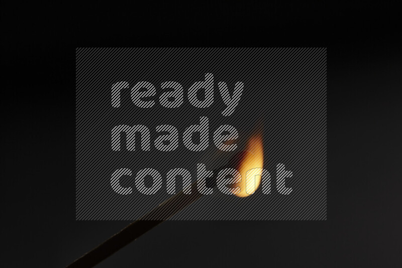 A burning matchstick isolated on dark backdrop