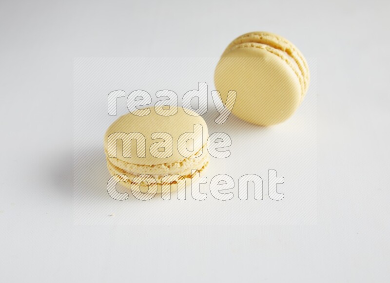 45º Shot of two Yellow Vanilla macarons on white background