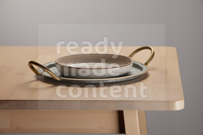 multicolored plate placed on a rounded stainless steel tray with golden handels on the edge of wooden table