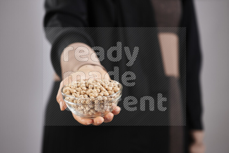 Woman in abaya holding different kinds of legumes in different positions