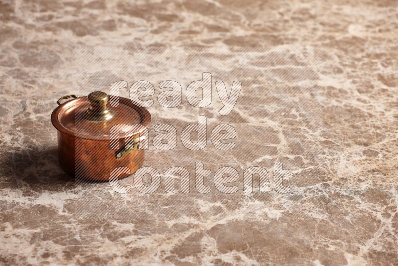 A small copper pot on beige marble background
