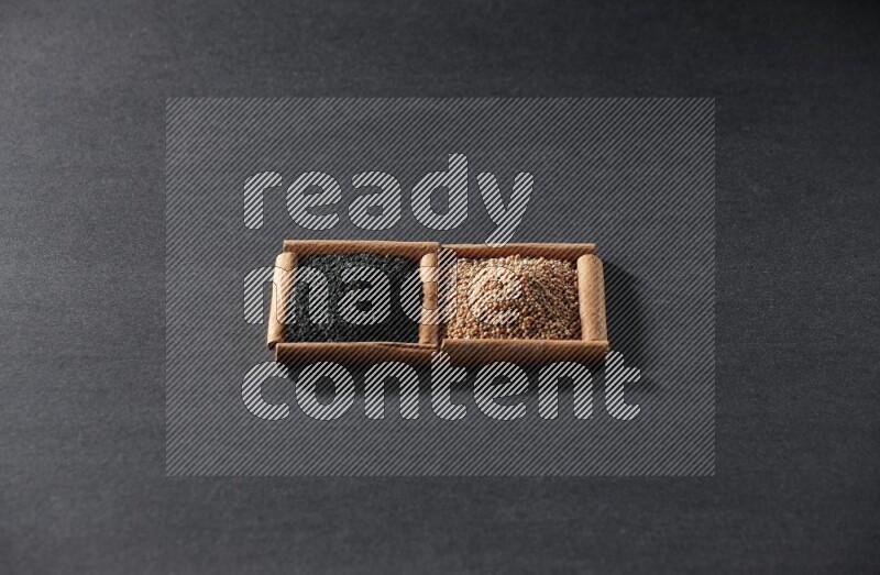 2 squares of cinnamon sticks full of mustard seeds and black seeds on black flooring