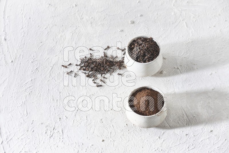 وعاءين من السيراميك بيج اللون، أحدهما مملوء بالقرنفل والآخر مملوء بالبودرة على أرضية بيضاء