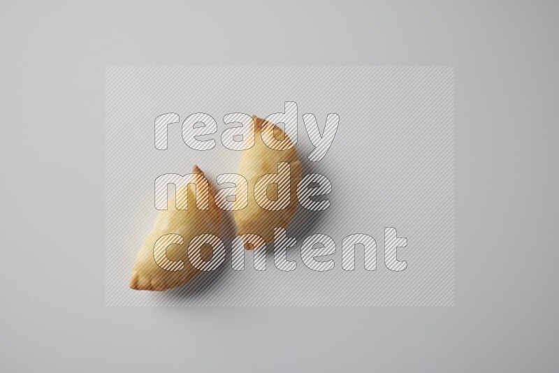 Two fried sambosa from a top angle on a white background