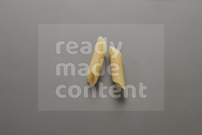 Mini penne pasta on grey background