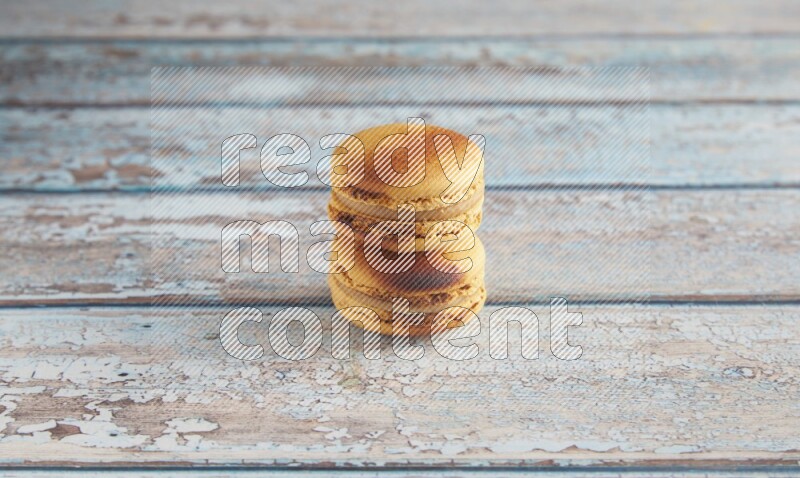 45º Shot of two Yellow Crème Brulée macarons on light blue wooden background